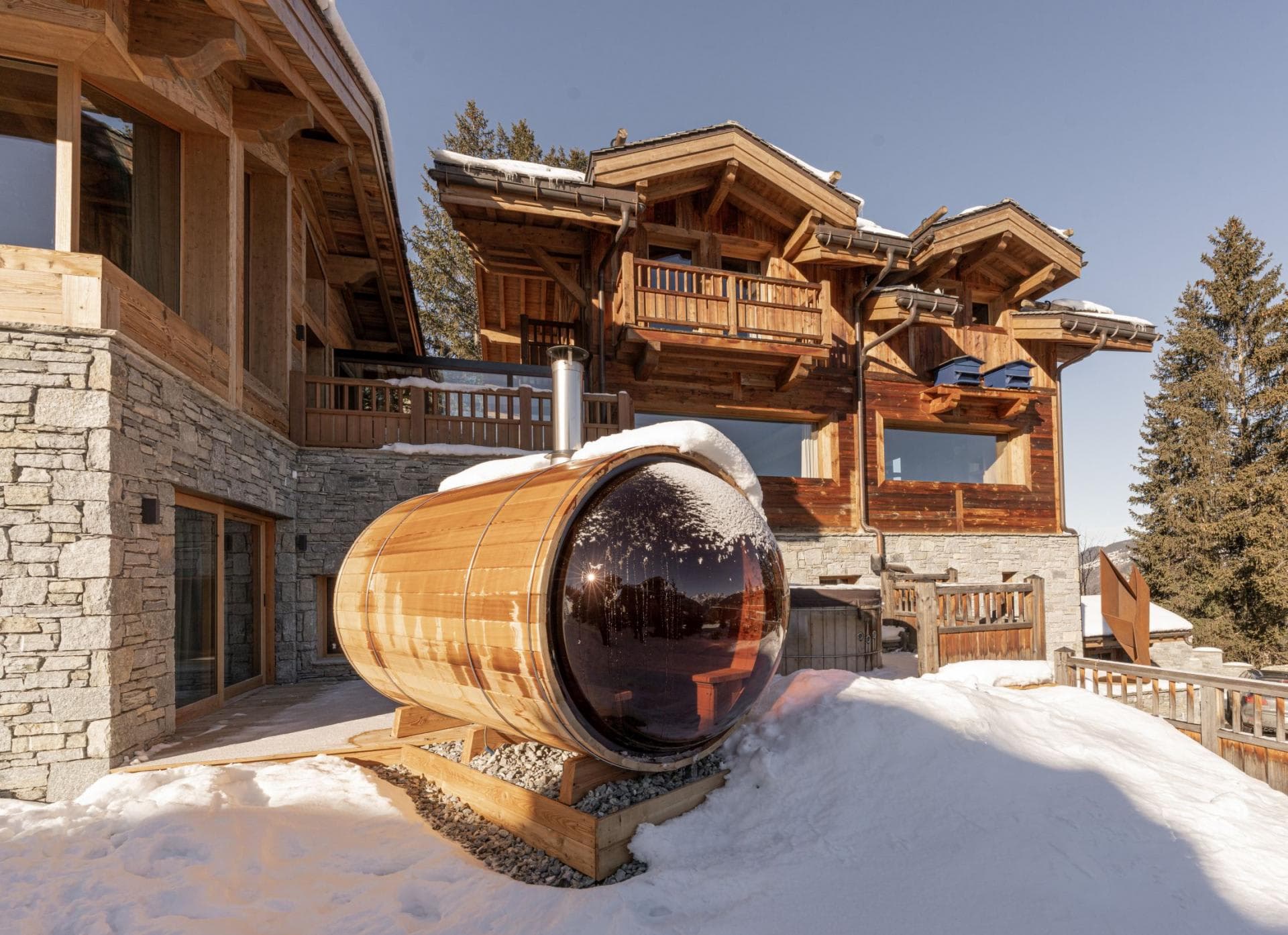 Outdoor barrel sauna with panoramic bubble window and wood-fired heater