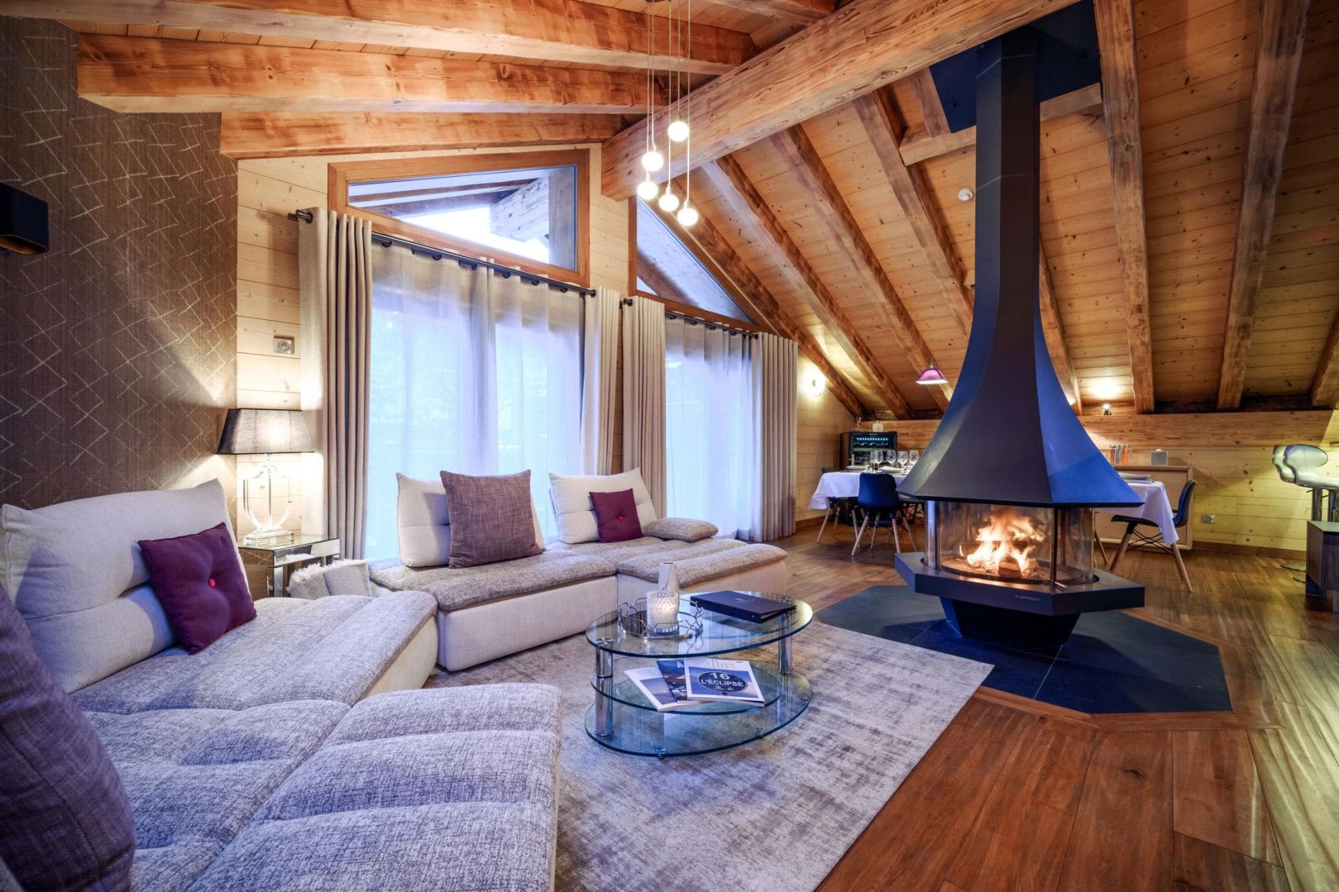 Living area with 360-degree central fireplace and vaulted timber ceilings