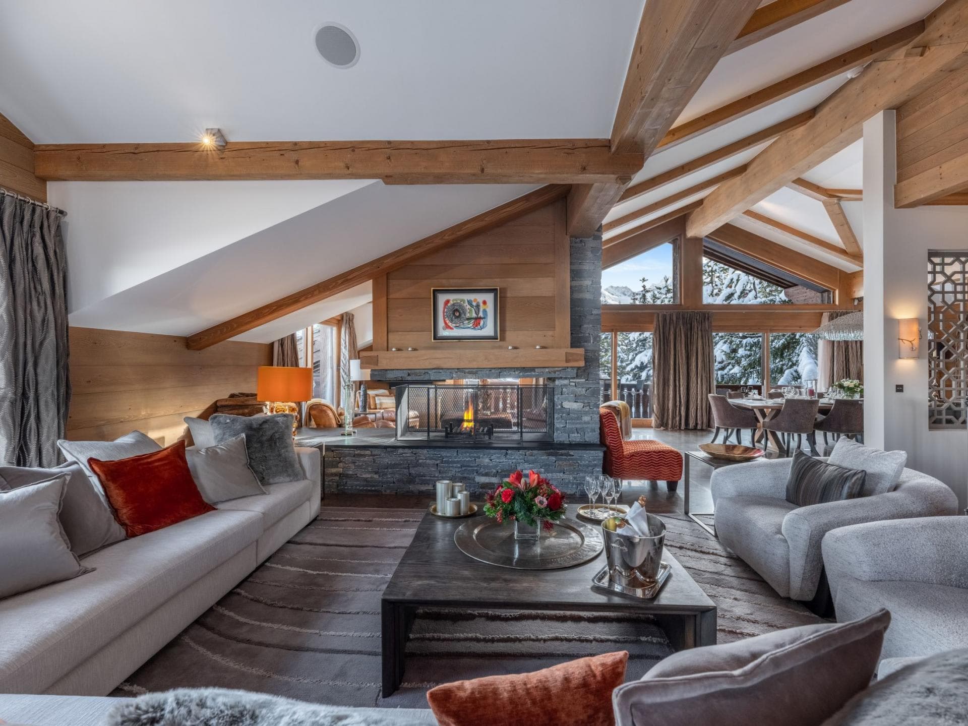Open-plan living area with double-sided stone fireplace and vaulted timber ceilings