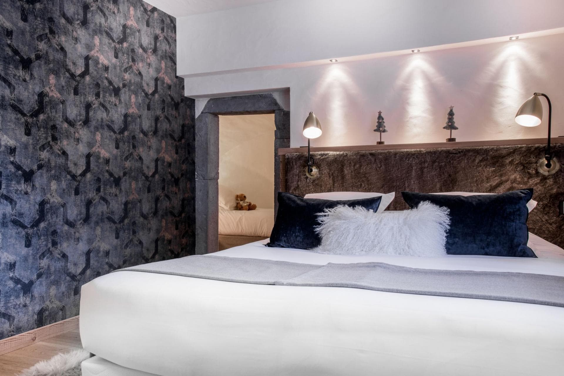 Bedroom with king bed and stone archway to adjoining sleeping area