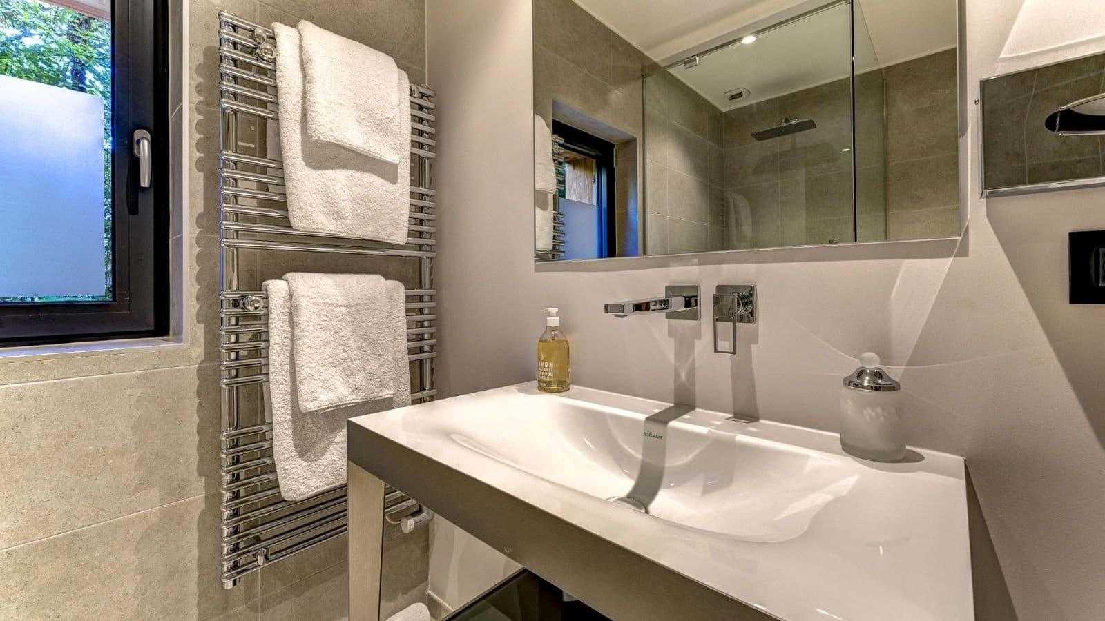 Bathroom featuring heated towel rack and wall-mounted faucets