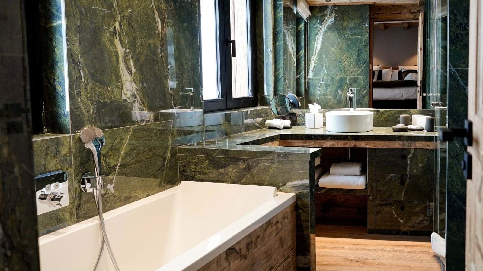 En suite bathroom with green marble walls and soaking tub
