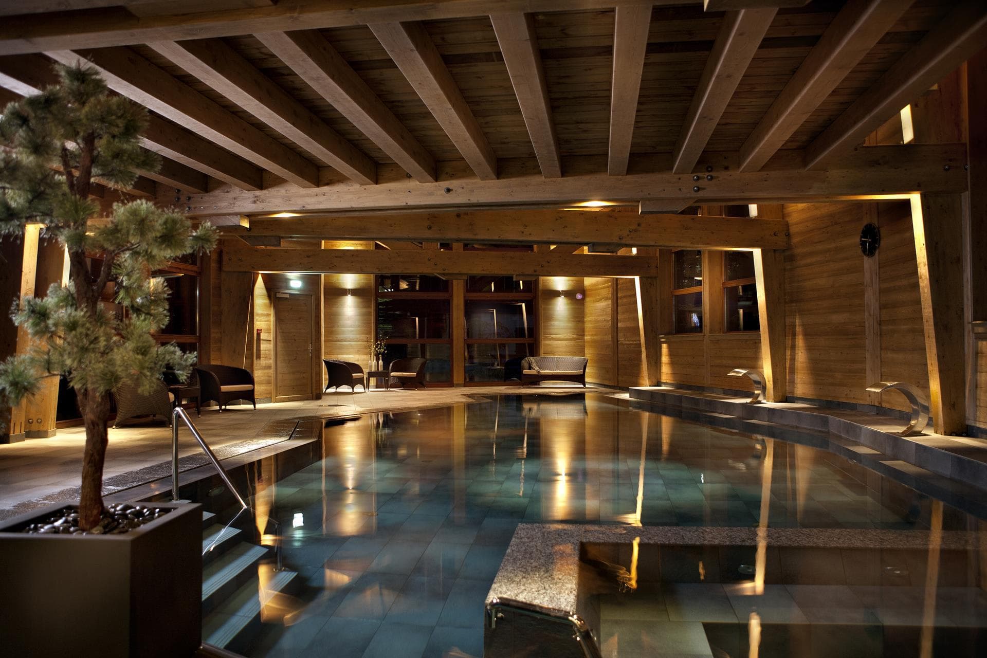Indoor heated pool with wood-beam ceiling and waterfall features