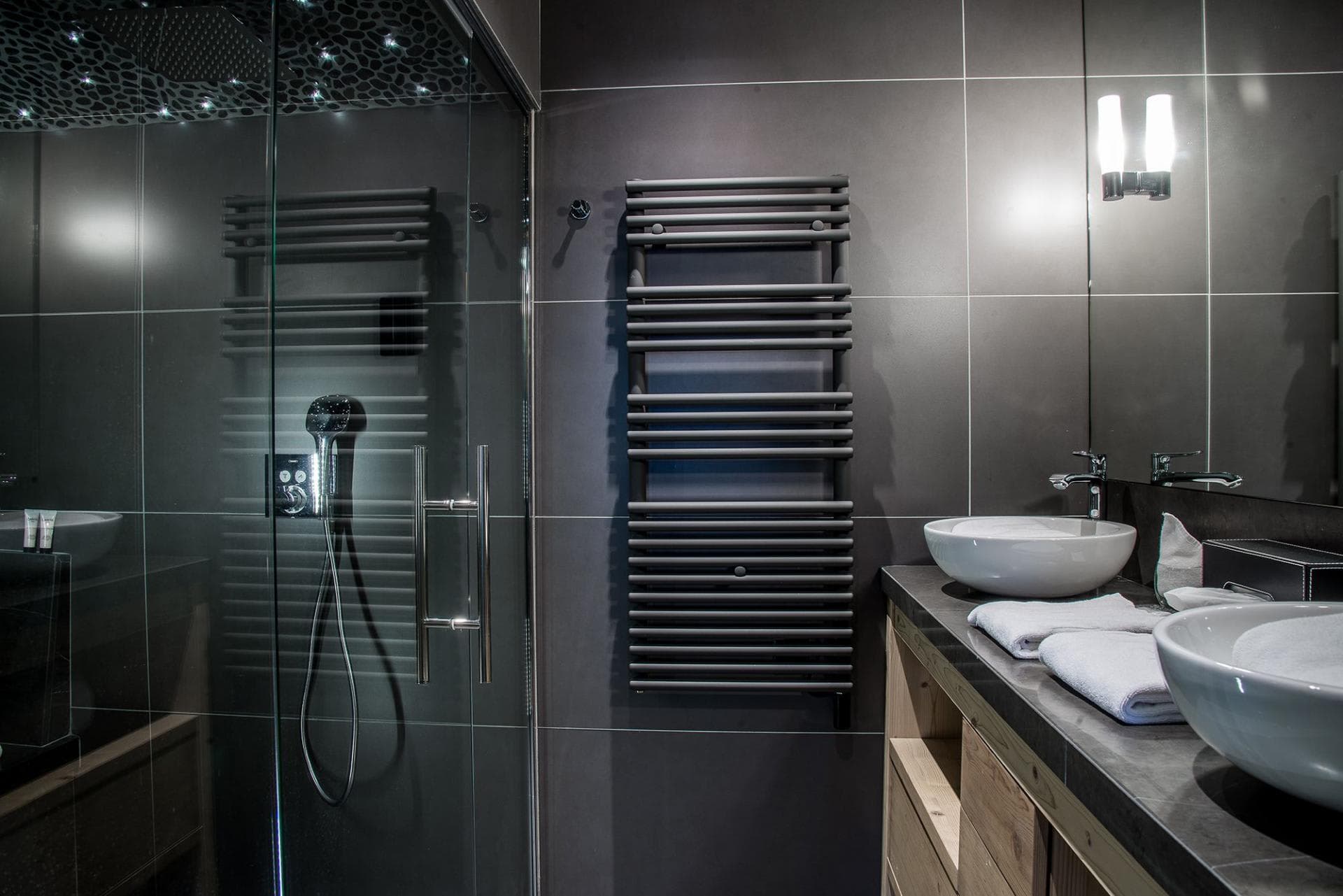 Bathroom with dual vessel sinks, walk-in rainfall shower, and heated towel rack