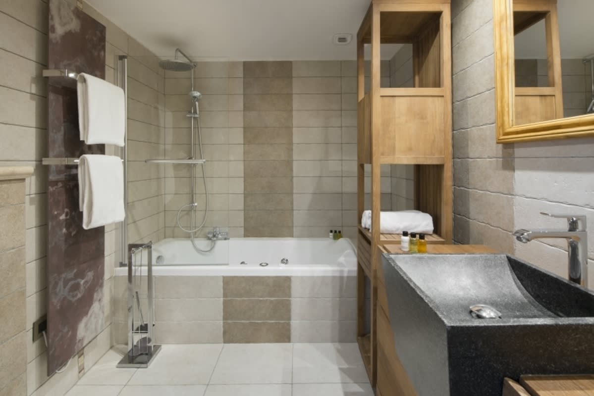 Bathroom with stone vessel sink, heated towel rack, and jetted soaking tub