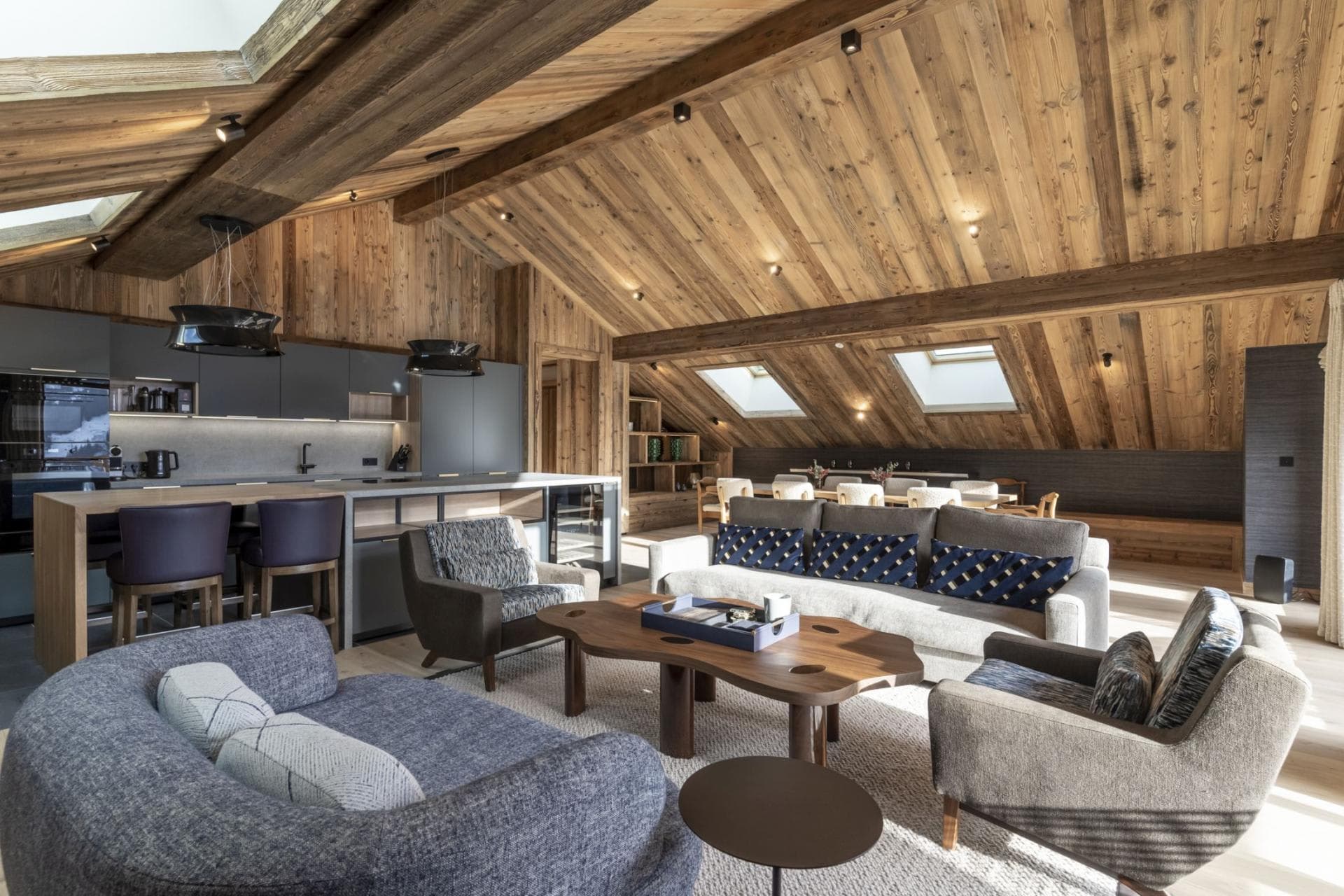 Open-plan living area with vaulted wood ceilings, breakfast bar, and wine fridge