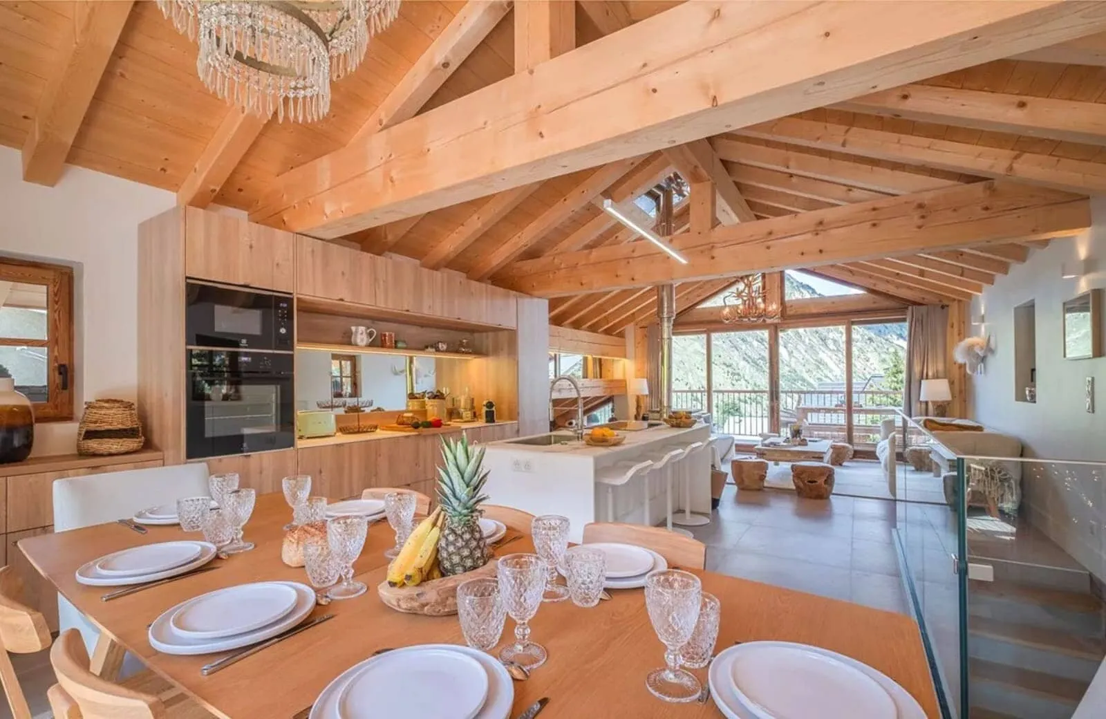 Open-plan living area with vaulted timber ceilings and floor-to-ceiling mountain views