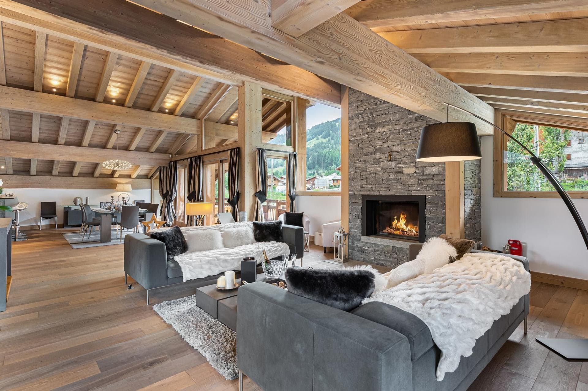 Living room with stone fireplace and vaulted beam ceilings; mountain views