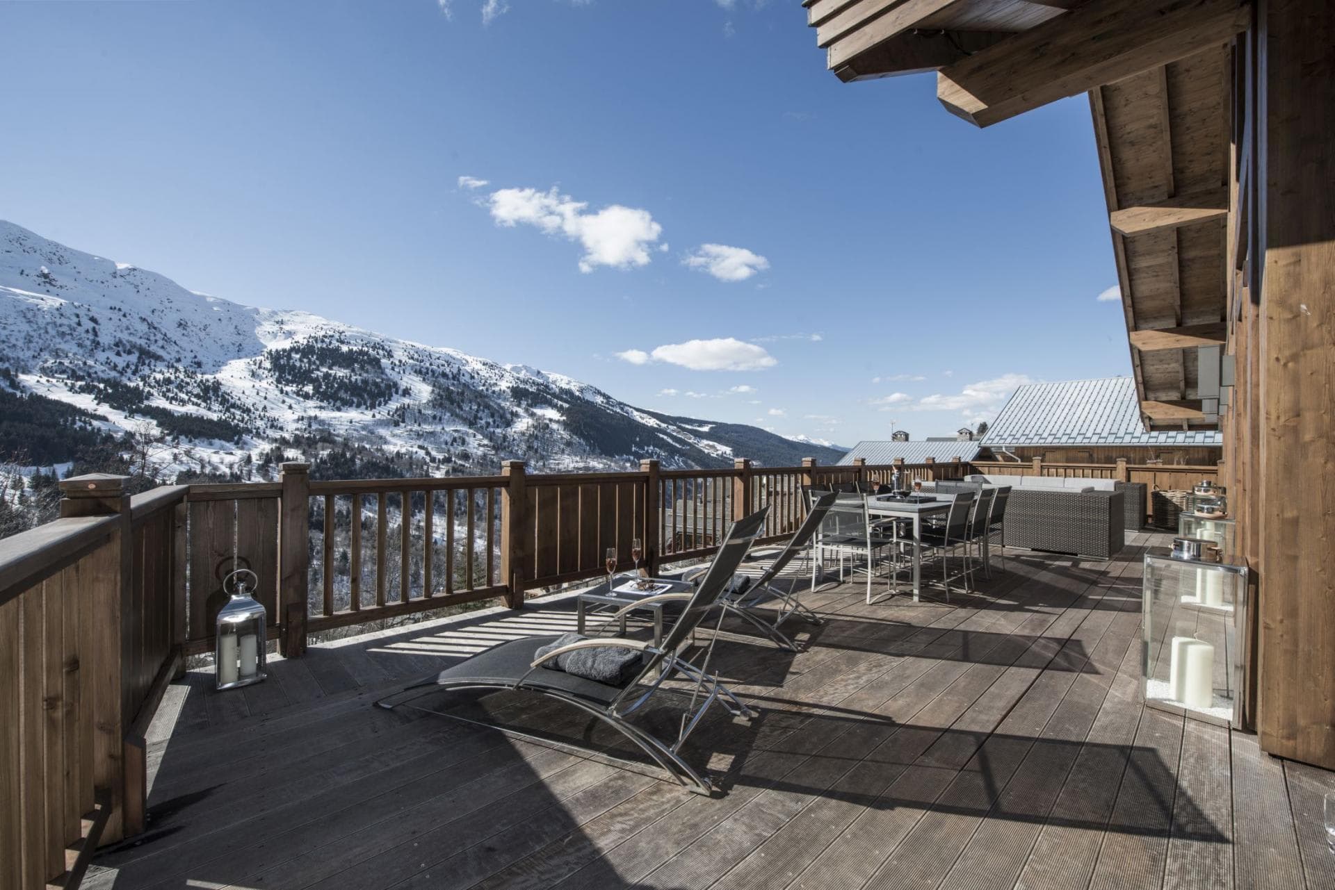 Wood deck with sun loungers and dining table; mountain views