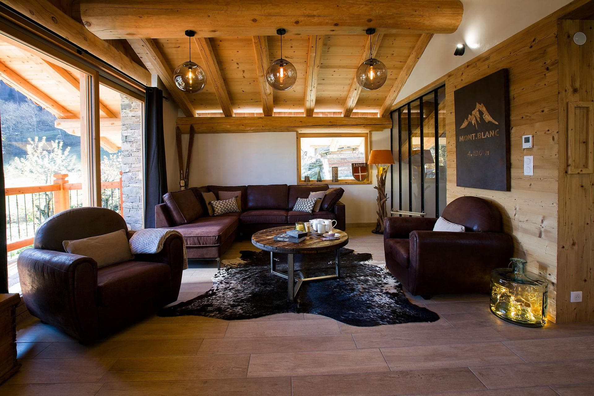 Living area with leather sectional, club chairs, and vaulted timber ceilings