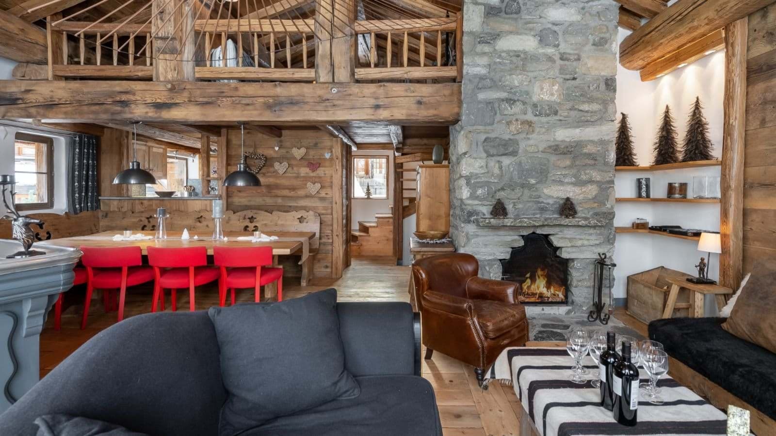 Open-plan living room with stone fireplace, leather seating, and mezzanine loft above