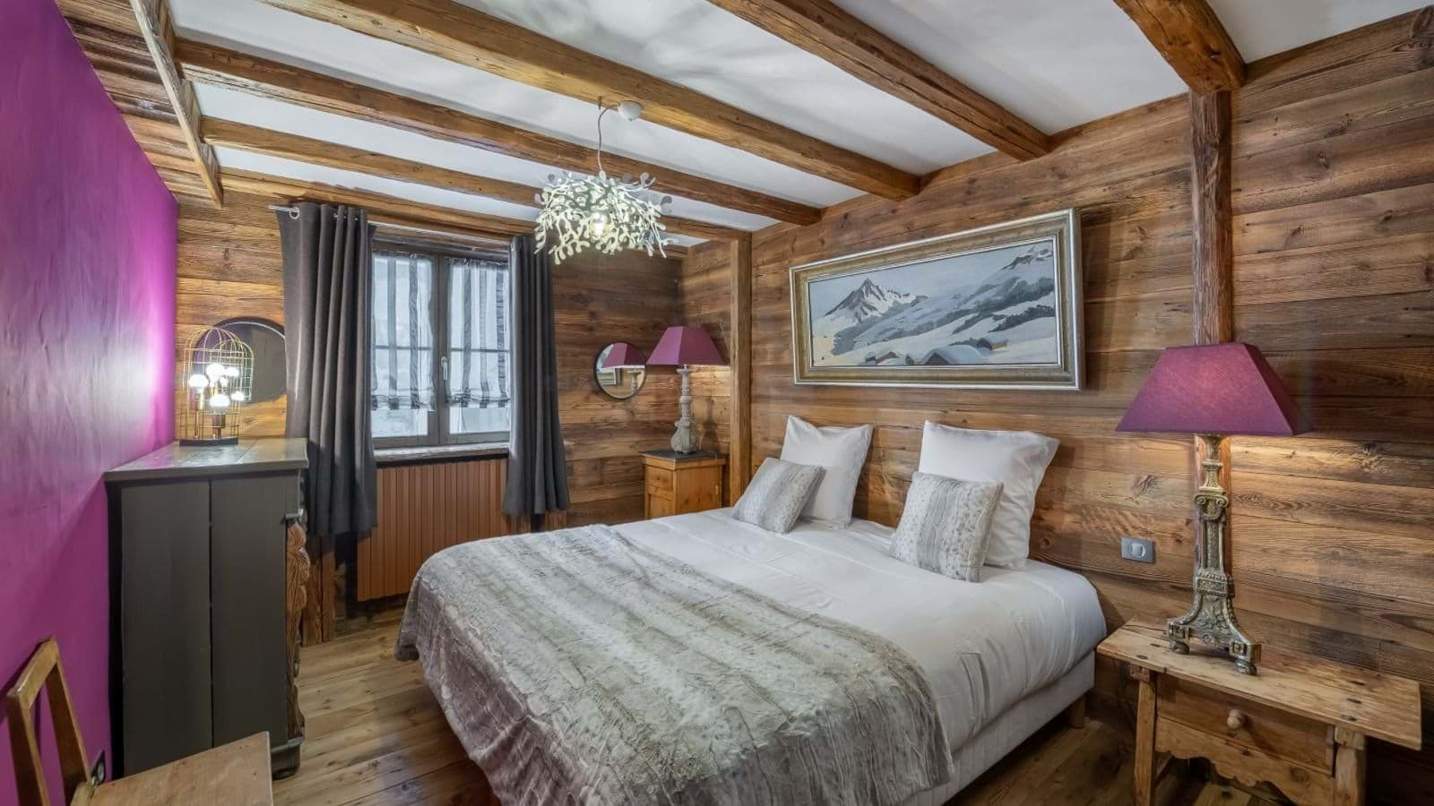 Bedroom with exposed beam ceiling and heated floor; mountain landscape artwork