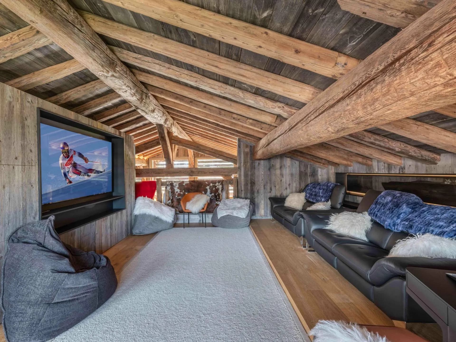 Room with television and seating beneath a sloping timber ceiling