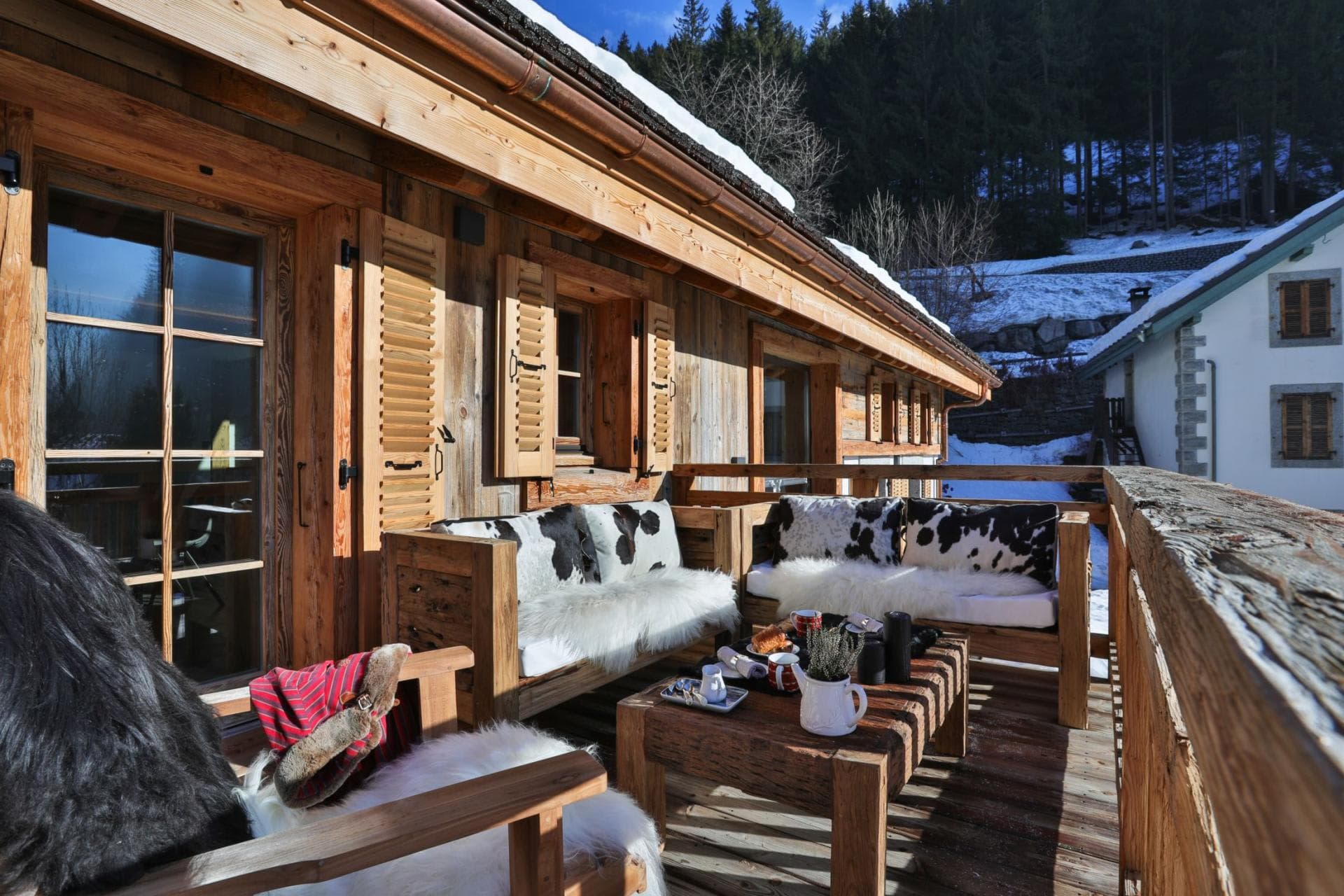 Private wooden balcony with built-in lounge seating and faux-fur textiles