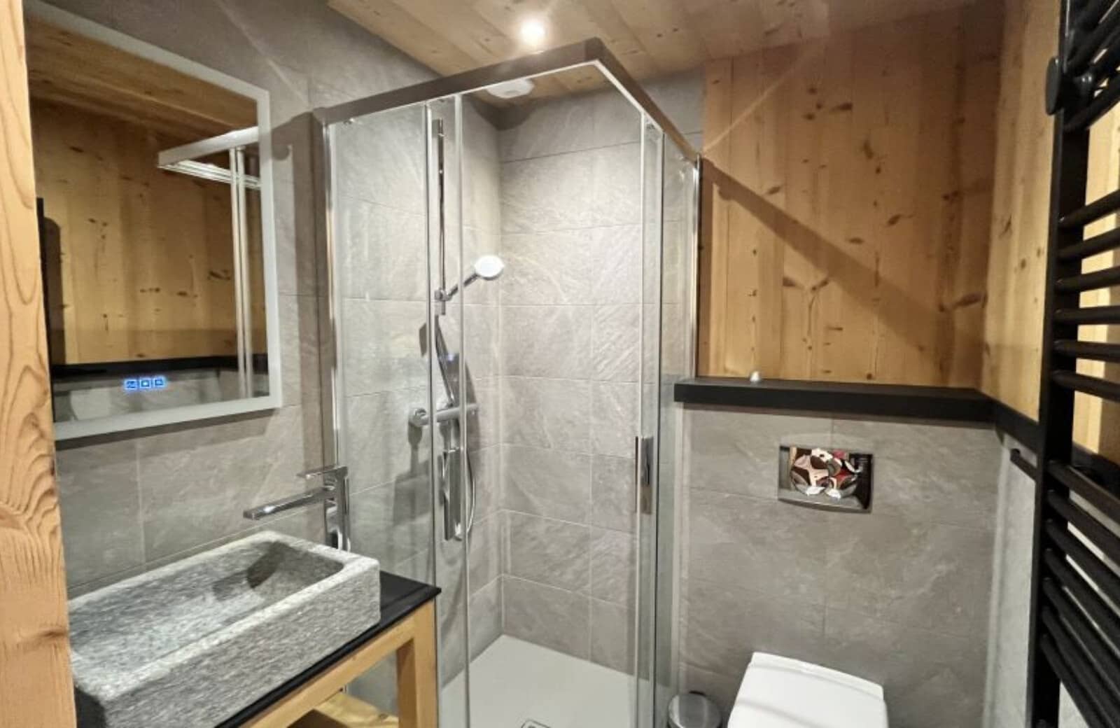 Bathroom with walk-in shower, stone sink, and heated towel rack