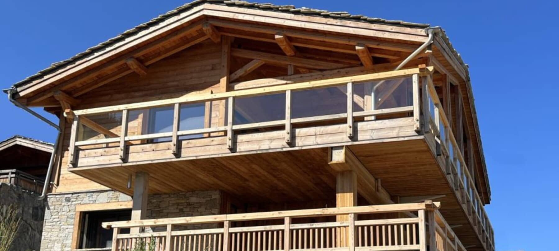 Chalet exterior with stacked balconies and glass railings on upper level
