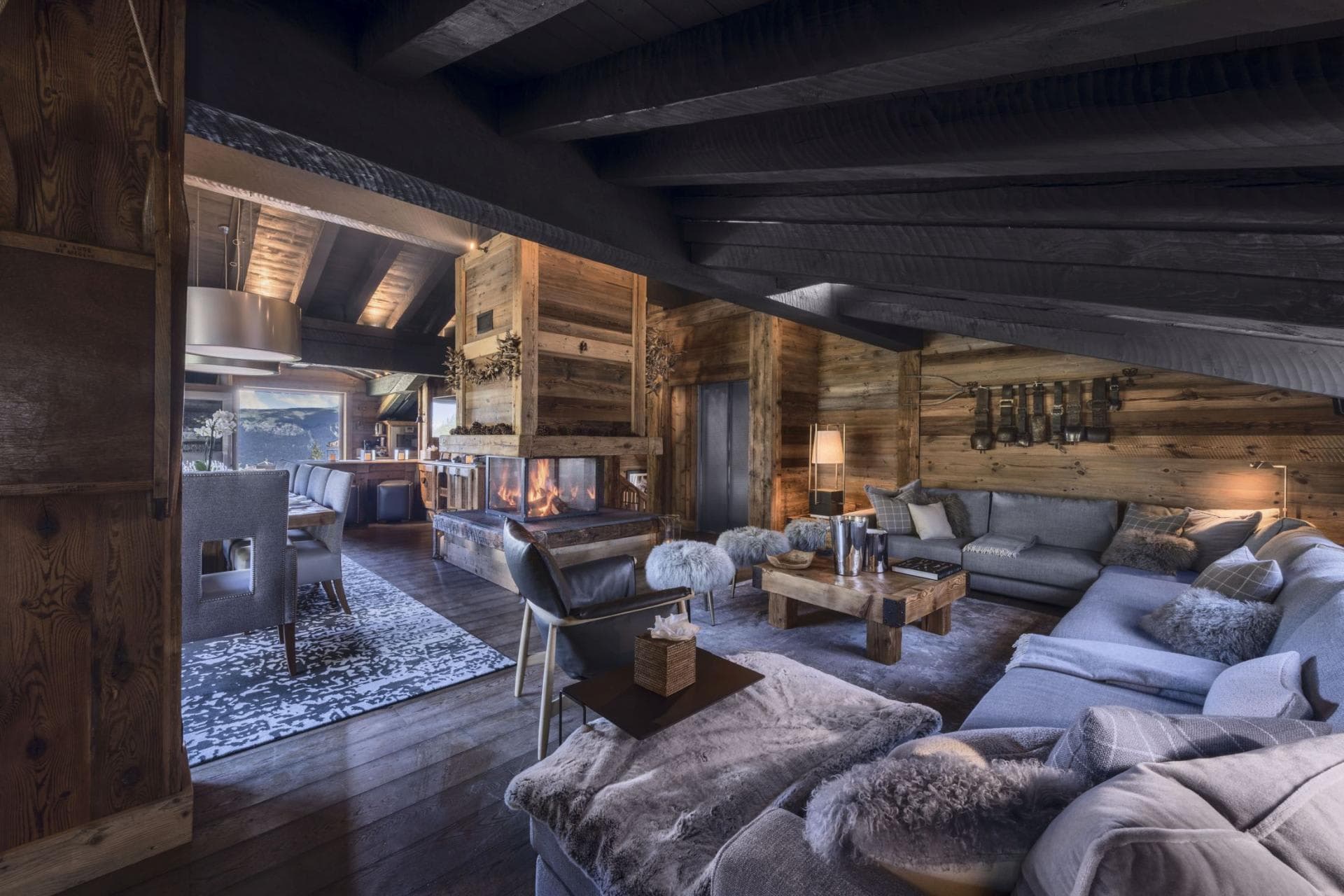 Open-plan living area with 3-sided glass fireplace and vaulted timber ceilings