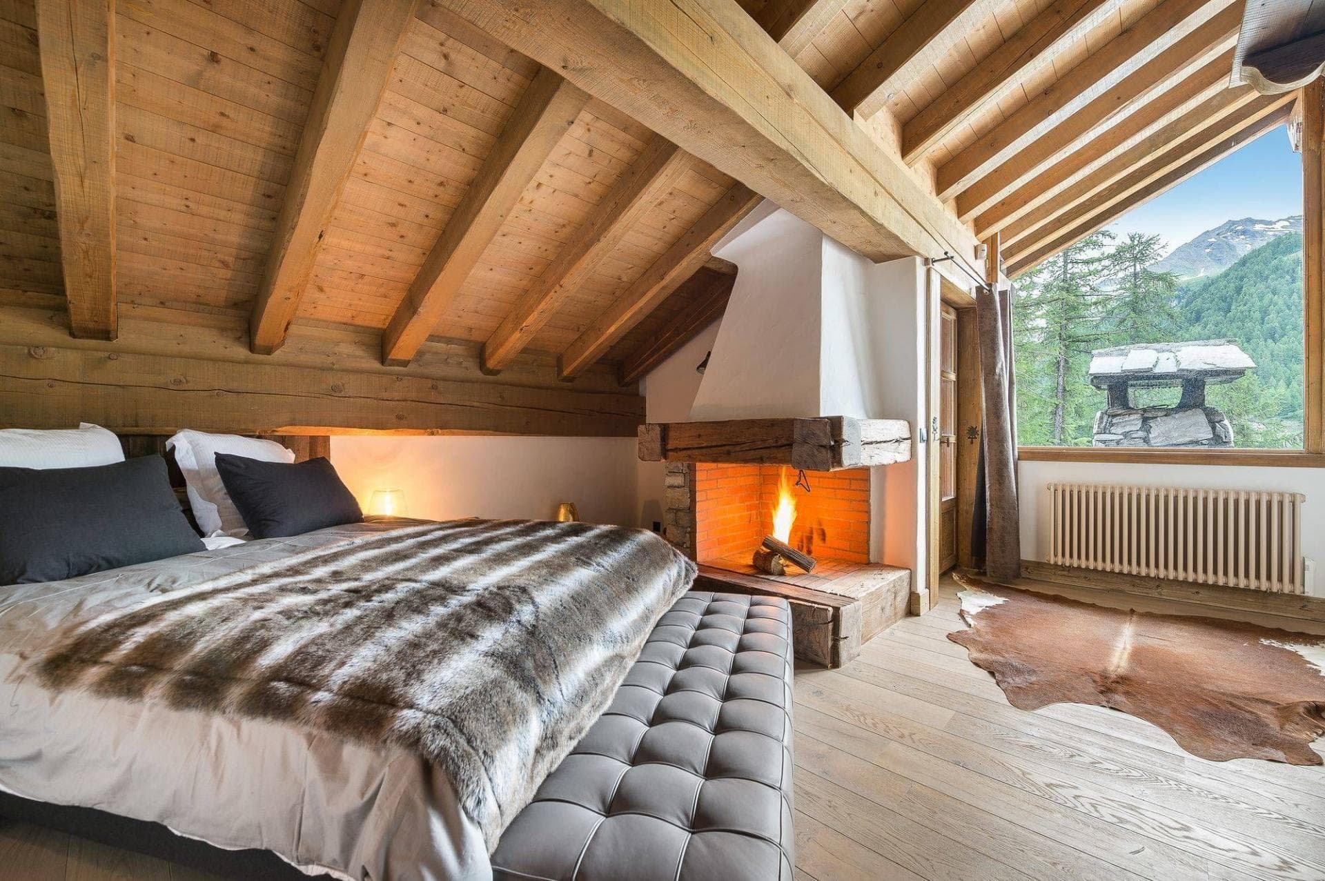 Bedroom with vaulted timber ceilings, wood-burning fireplace, and mountain views