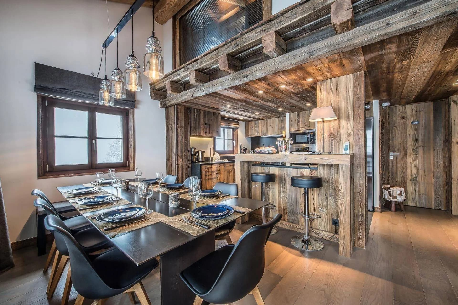 Dining table beneath timber beams beside the open kitchen
