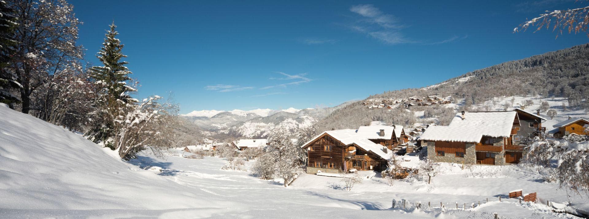 Snow-covered chalets with mountain valley views and nearby forest trails