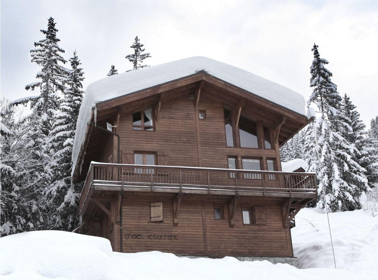 Timber chalet exterior with wraparound balcony and snow-covered grounds