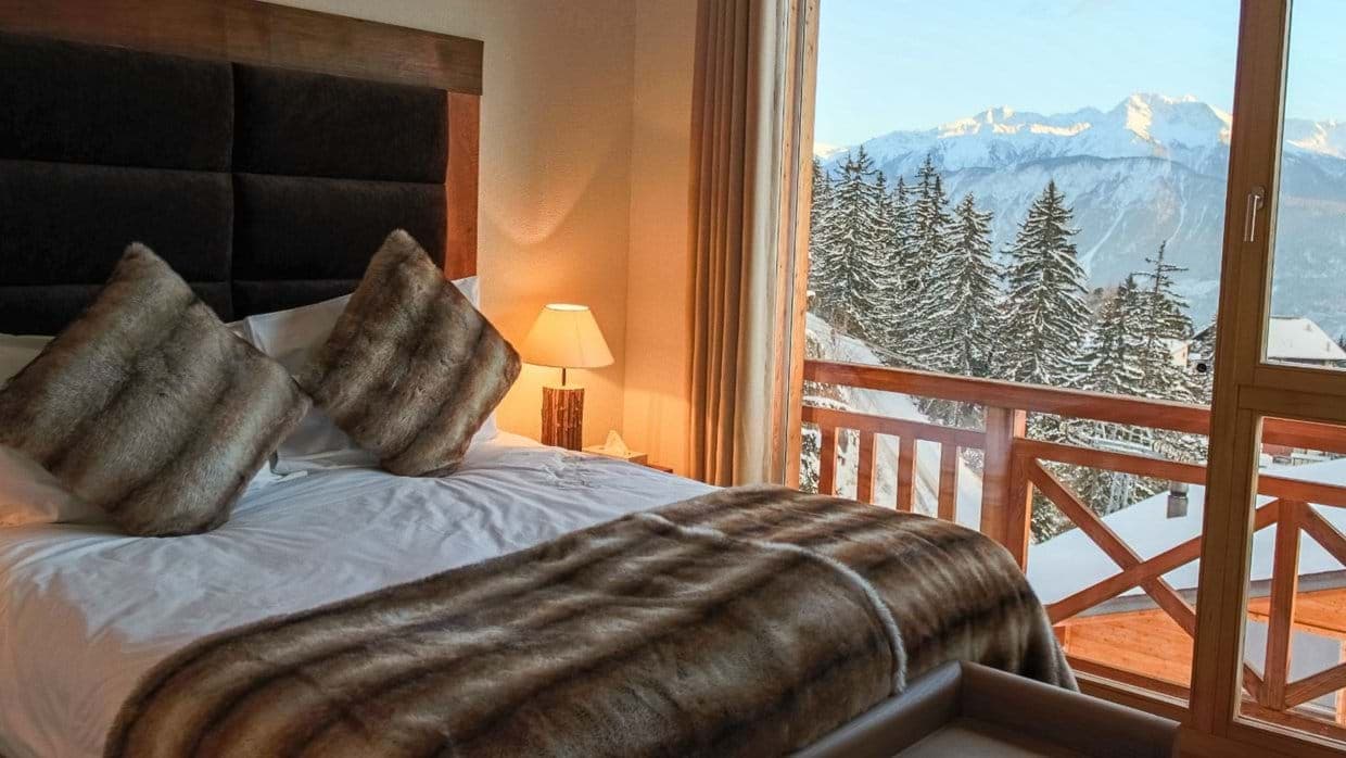 Bedroom with king bed and private balcony overlooking snowy mountains