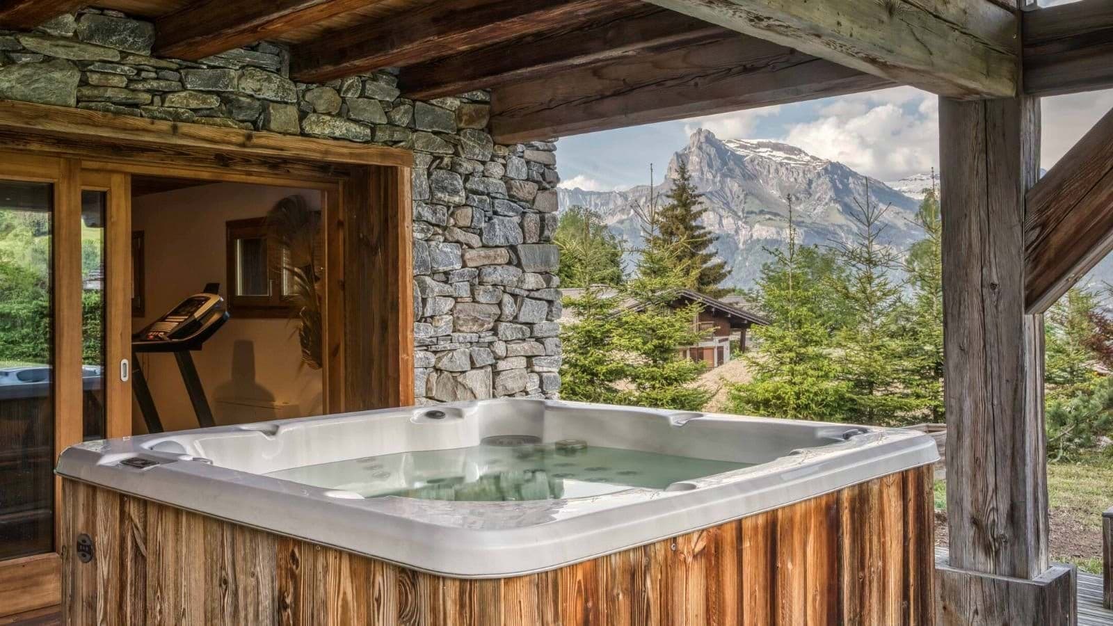 Covered outdoor hot tub with mountain views and adjacent fitness room