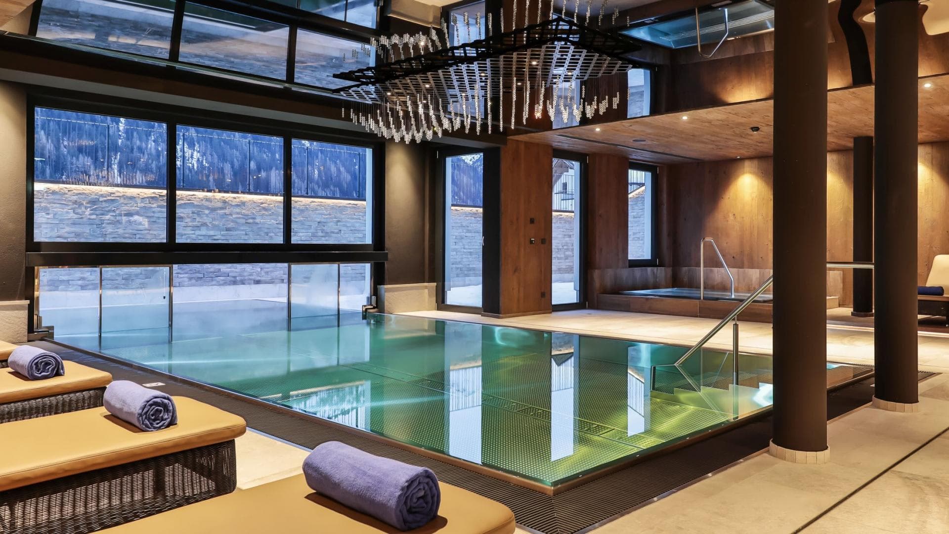 Indoor-outdoor swimming pool with mountain views and poolside loungers