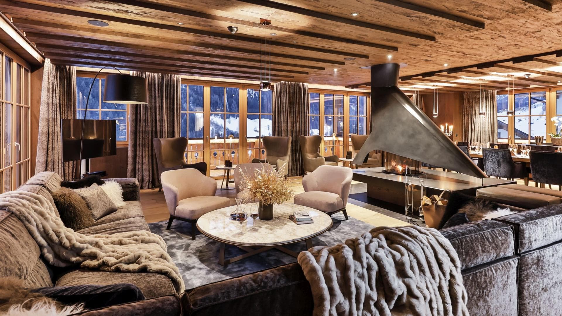 Living area with central 360-degree fireplace and alpine slope views
