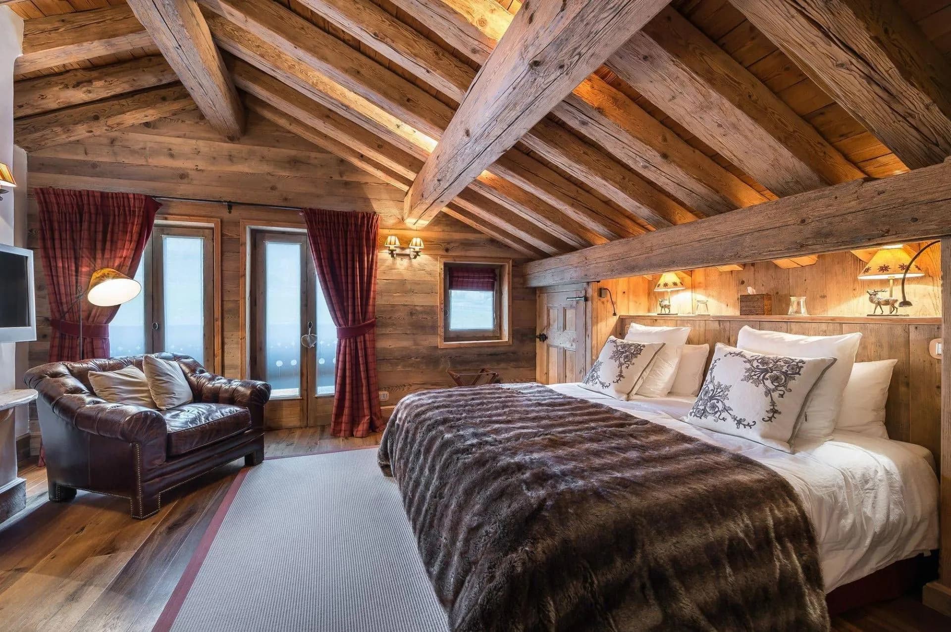 Double bedroom beneath timber beams with seating area