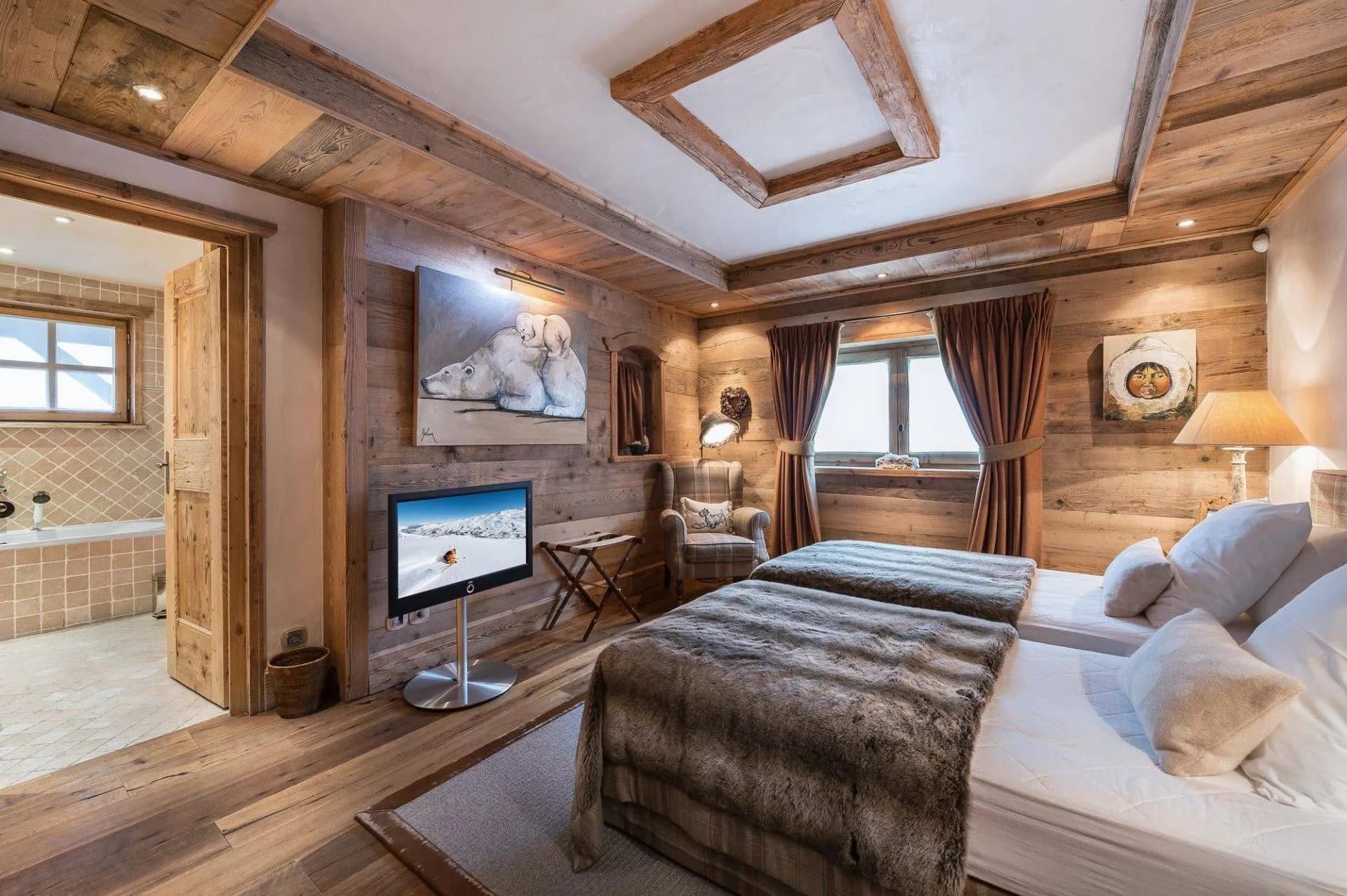 Double bedroom beneath timber beams with television and sofa seating