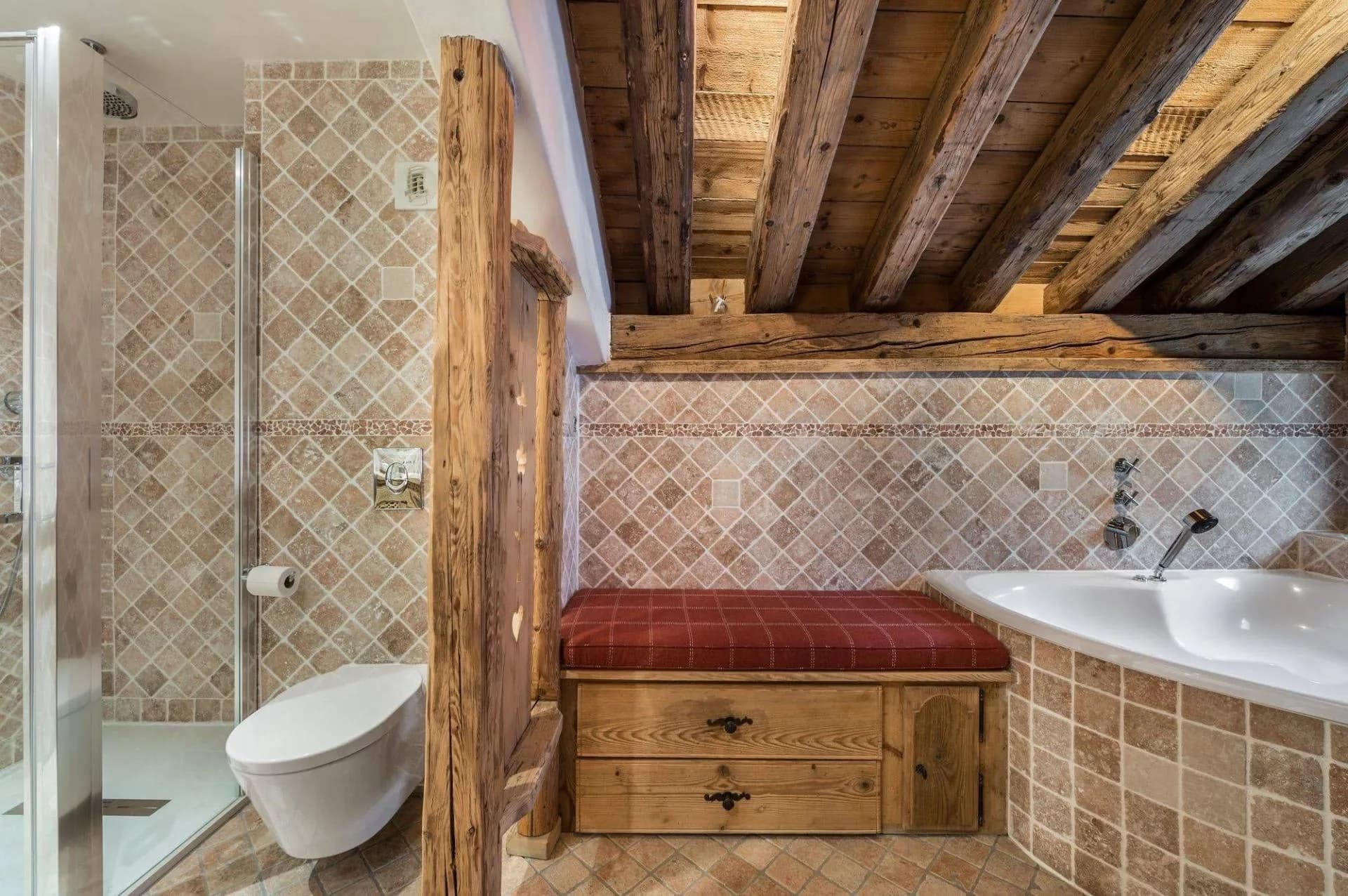 Bathroom with bathtub, shower, toilet and cushioned bench
