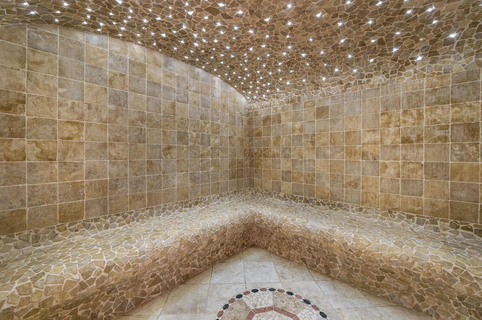 Gold-tiled hammam with curved seating and star-effect ceiling lights