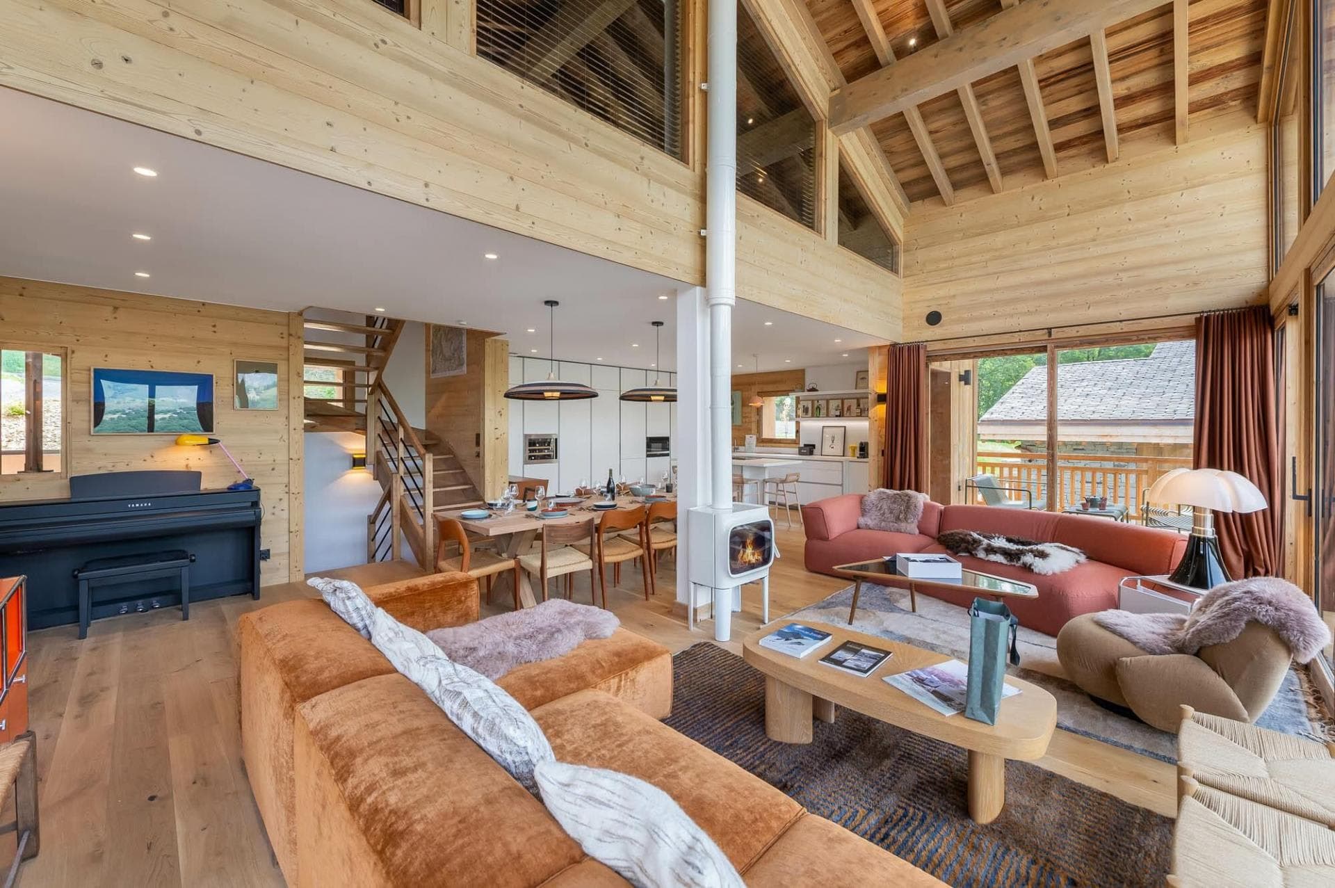 Open-plan living area with wood-burning stove, upright piano, and dining for 8