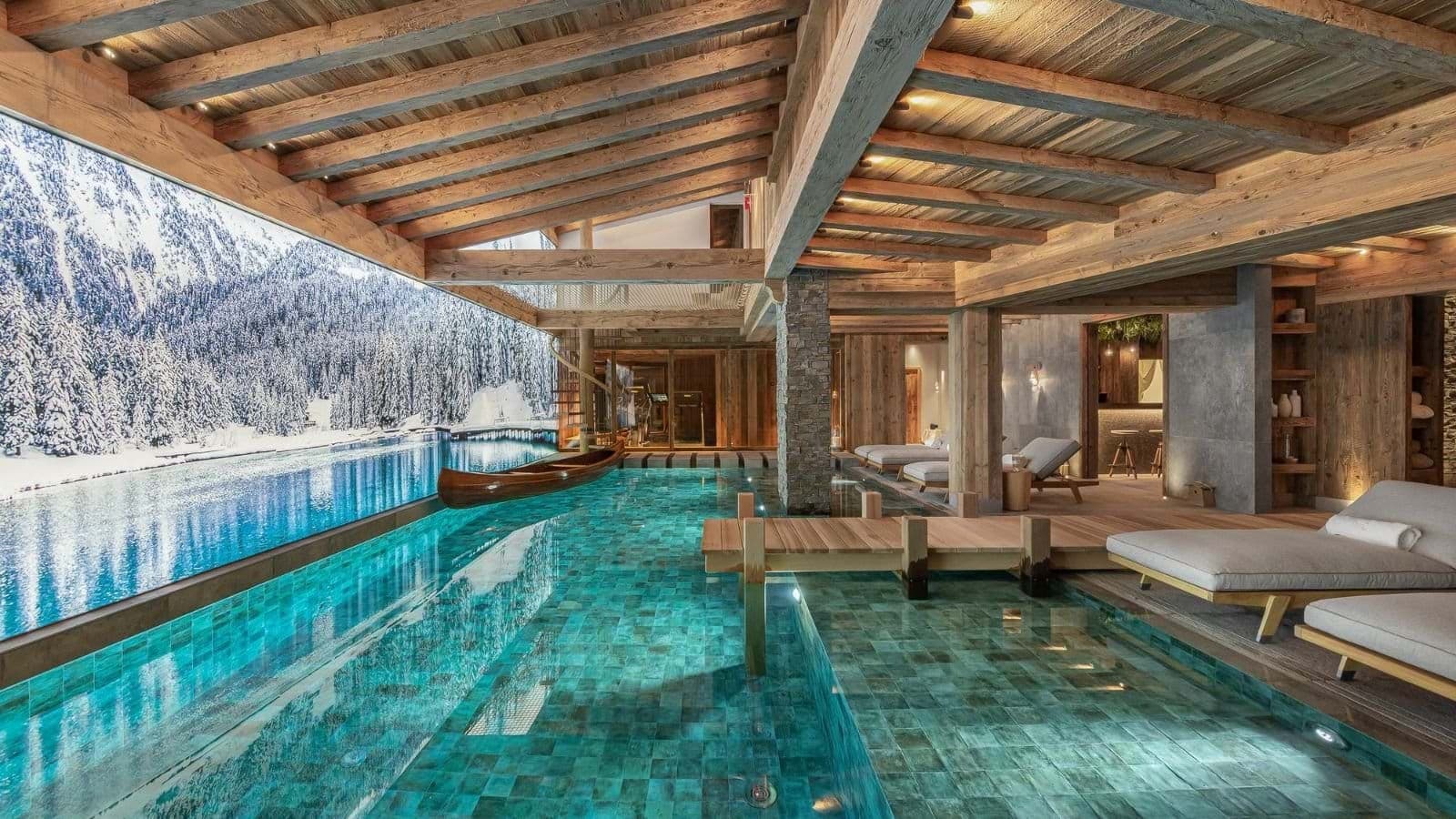 Indoor swimming pool with lounge seating and a panoramic alpine mural