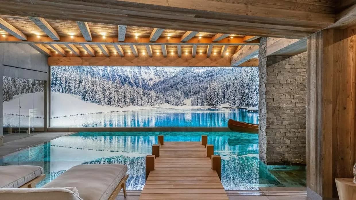 Indoor swimming pool with a wooden footbridge and panoramic alpine mural