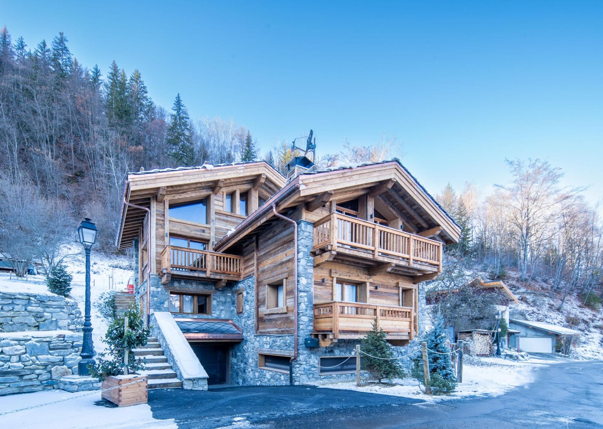 Timber and stone chalet with multiple decks; heated driveway visible