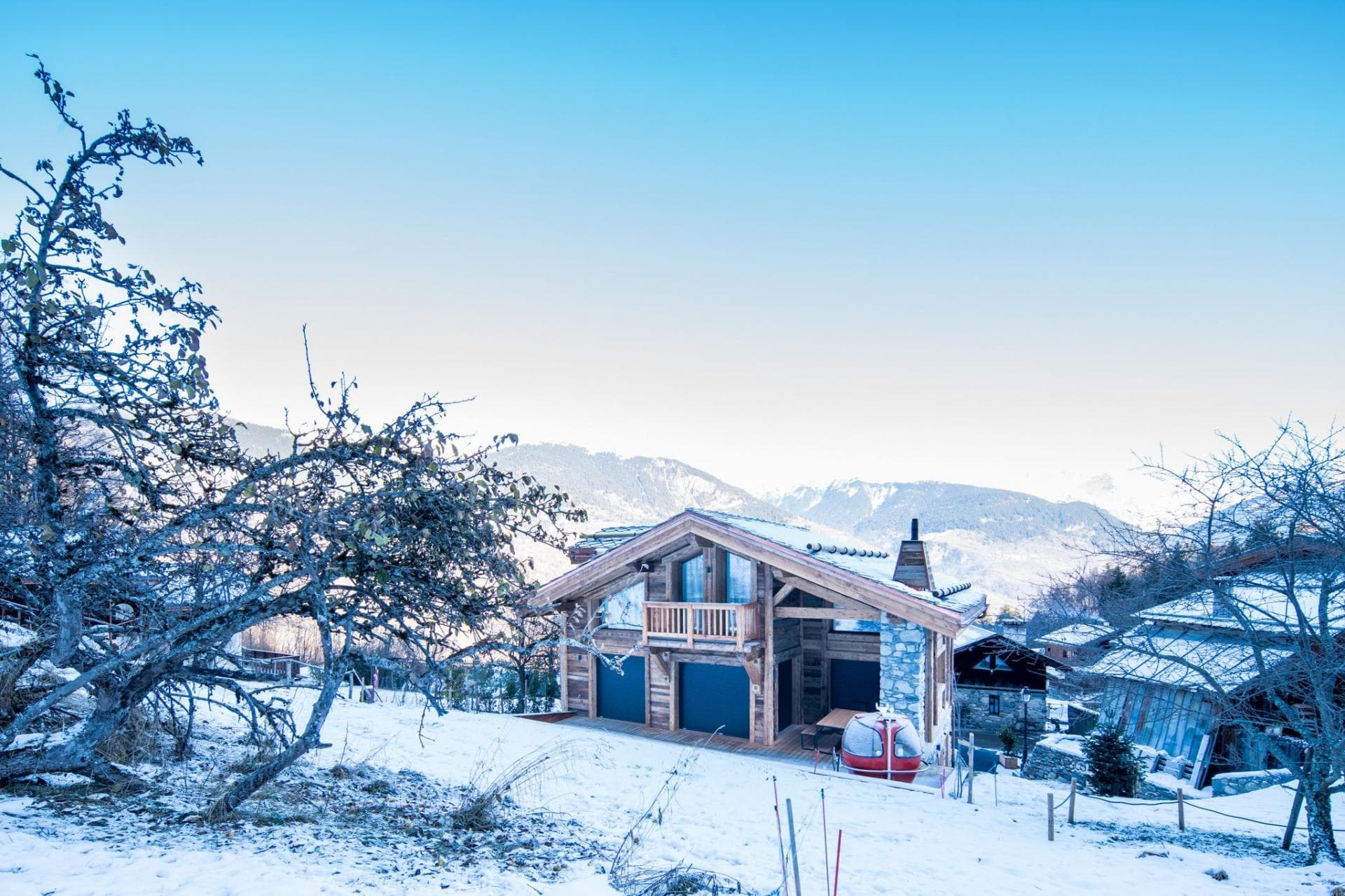 Ski chalet with attached garage; snow-covered grounds and mountain backdrop