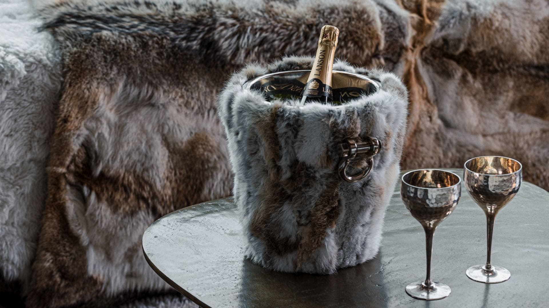 Champagne service with fur-wrapped ice bucket and hammered metal goblets