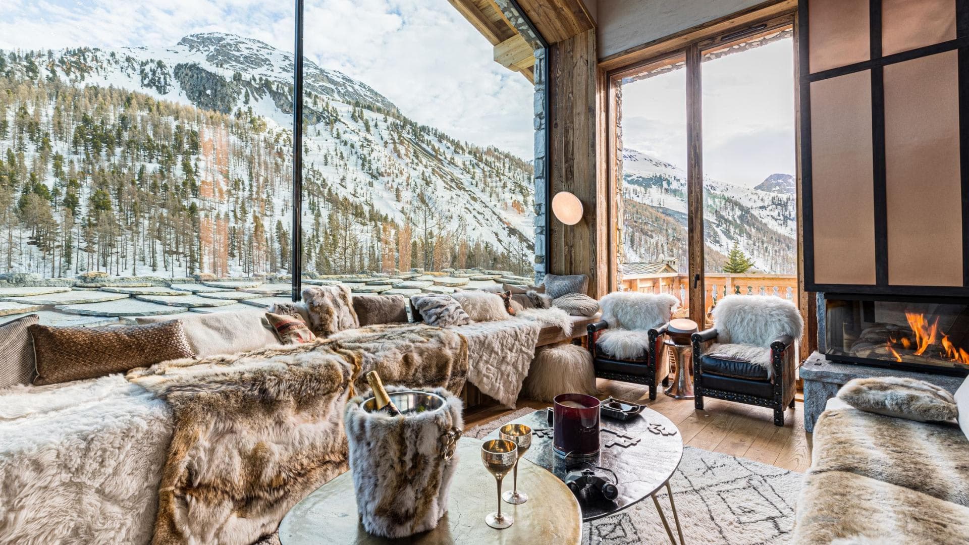 Lounge with wood fireplace and floor-to-ceiling mountain views