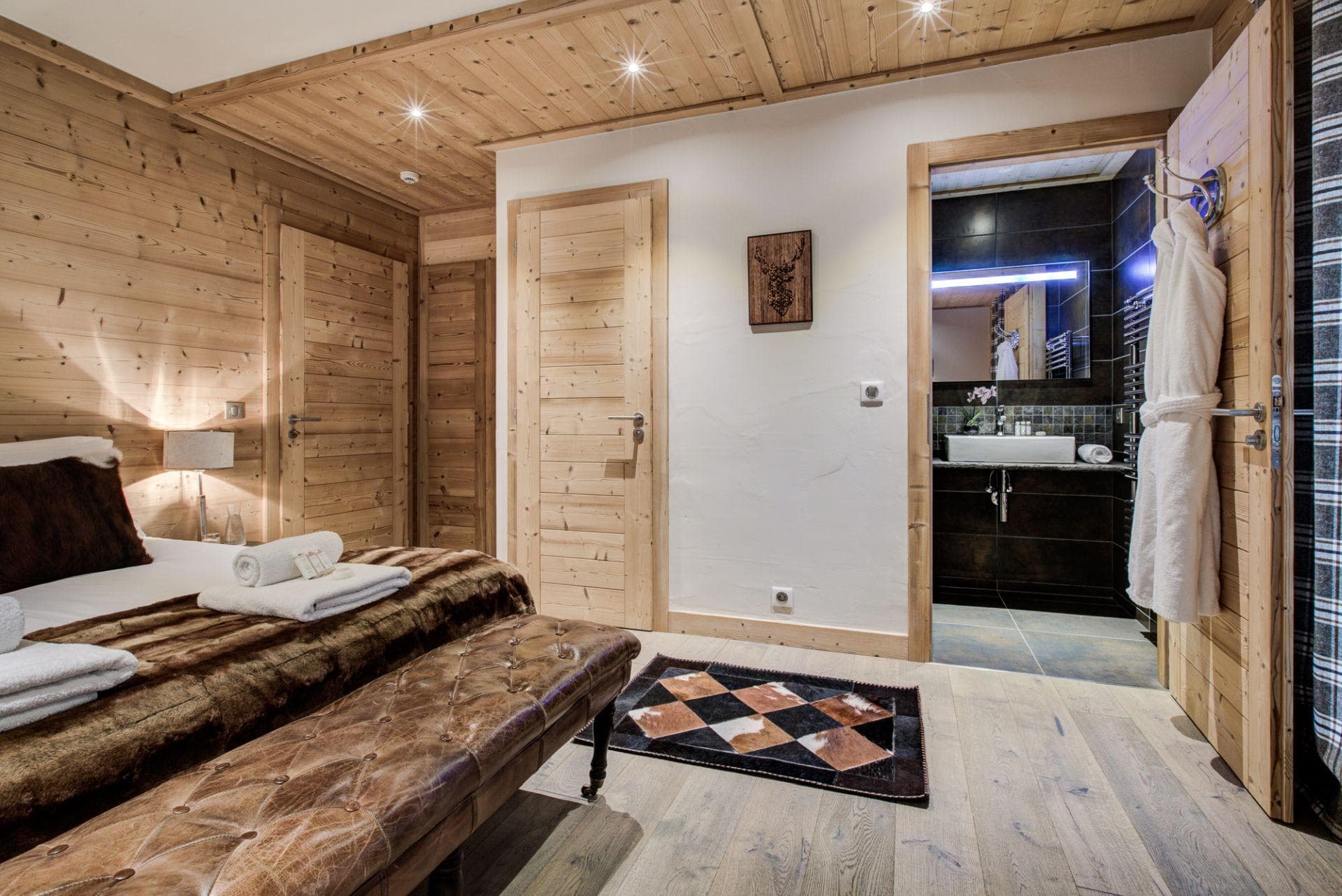 Wood-paneled bedroom with ensuite bathroom and tufted leather bench