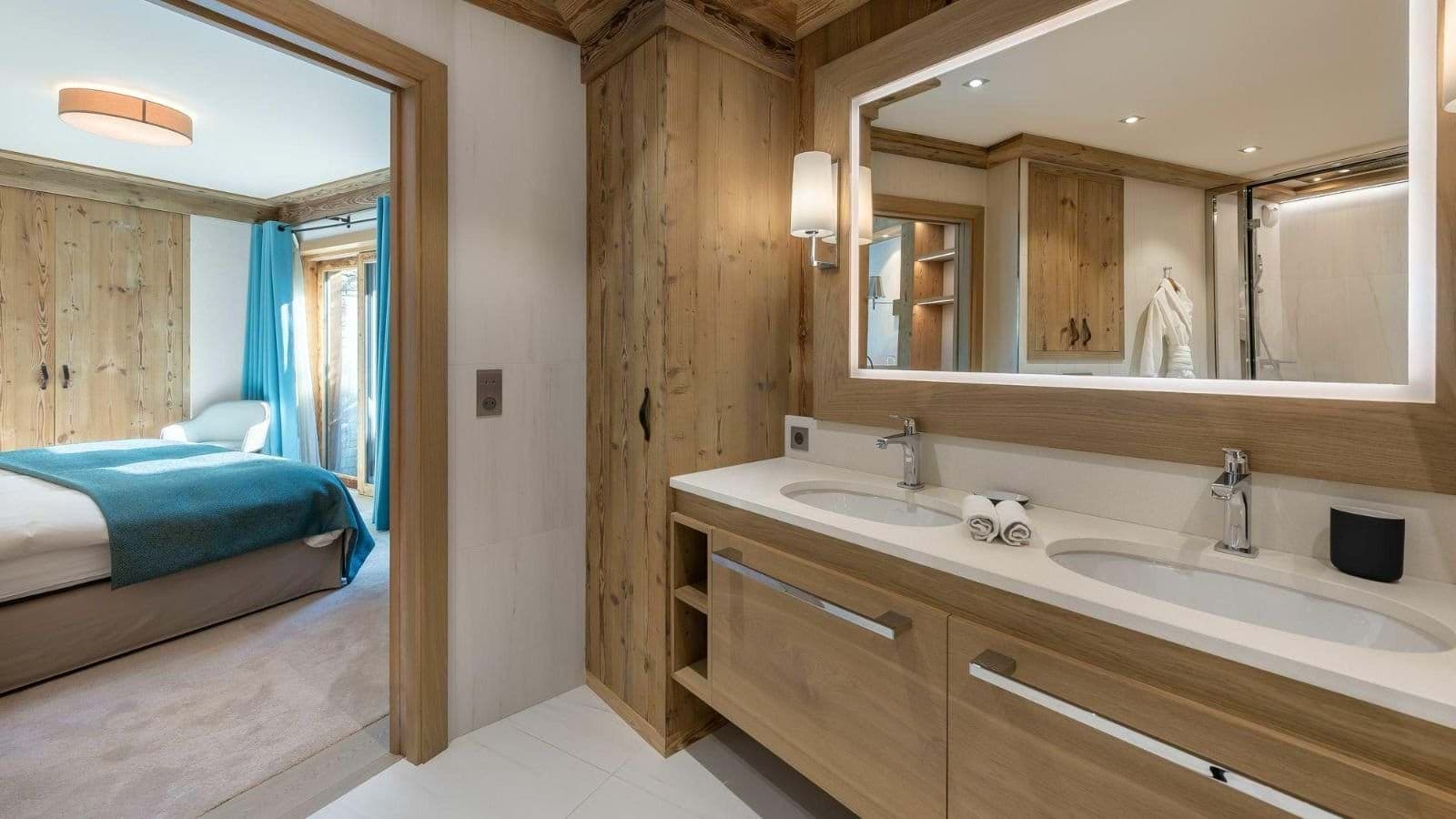 Ensuite bathroom with dual vanity and backlit mirror adjoining bedroom