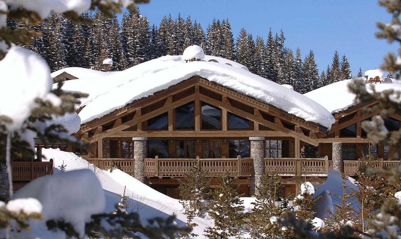 Ski-in chalet exterior with wraparound balcony and forest backdrop