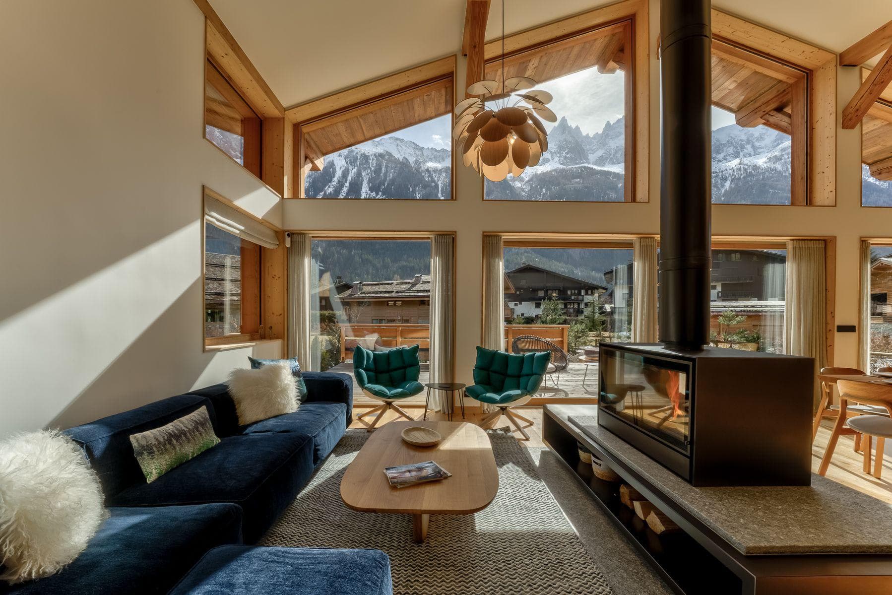Living room with central wood stove and floor-to-ceiling mountain views