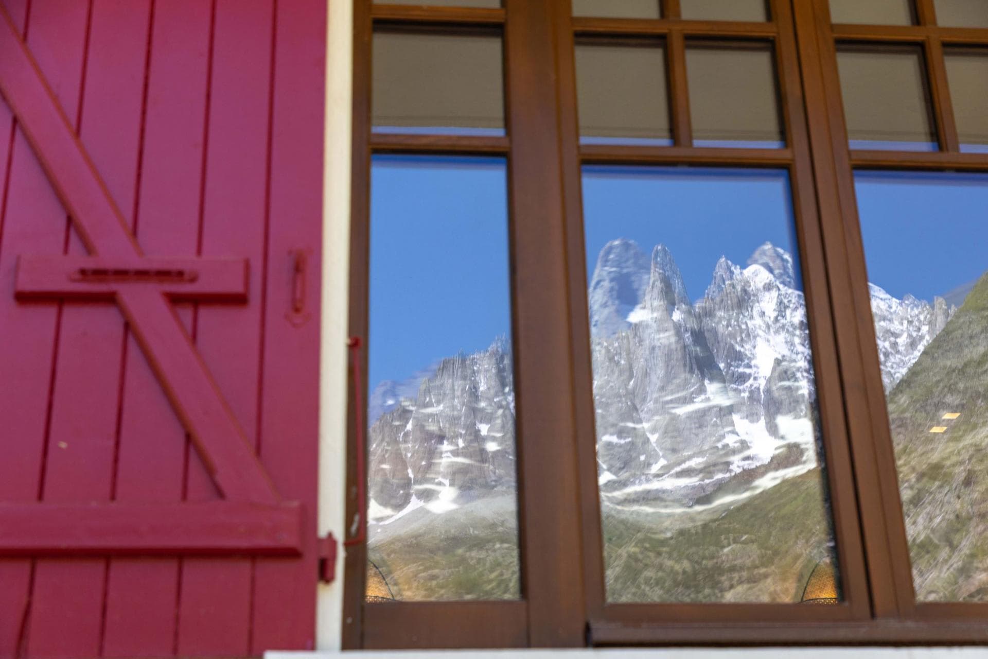 Traditional red shutters frame views of the surrounding mountain peaks