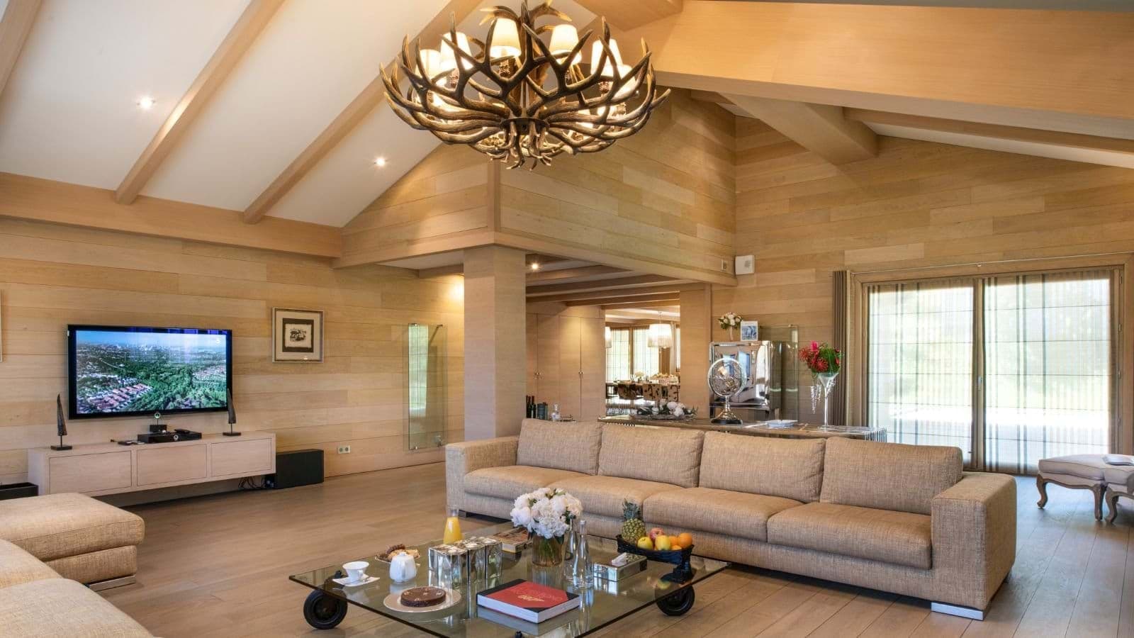 Living room with vaulted wood ceilings, antler chandelier, and sectional seating