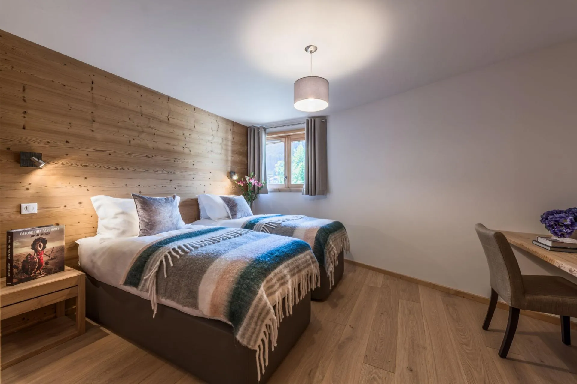 Bedroom arranged with twin beds, a wood-panelled wall and desk