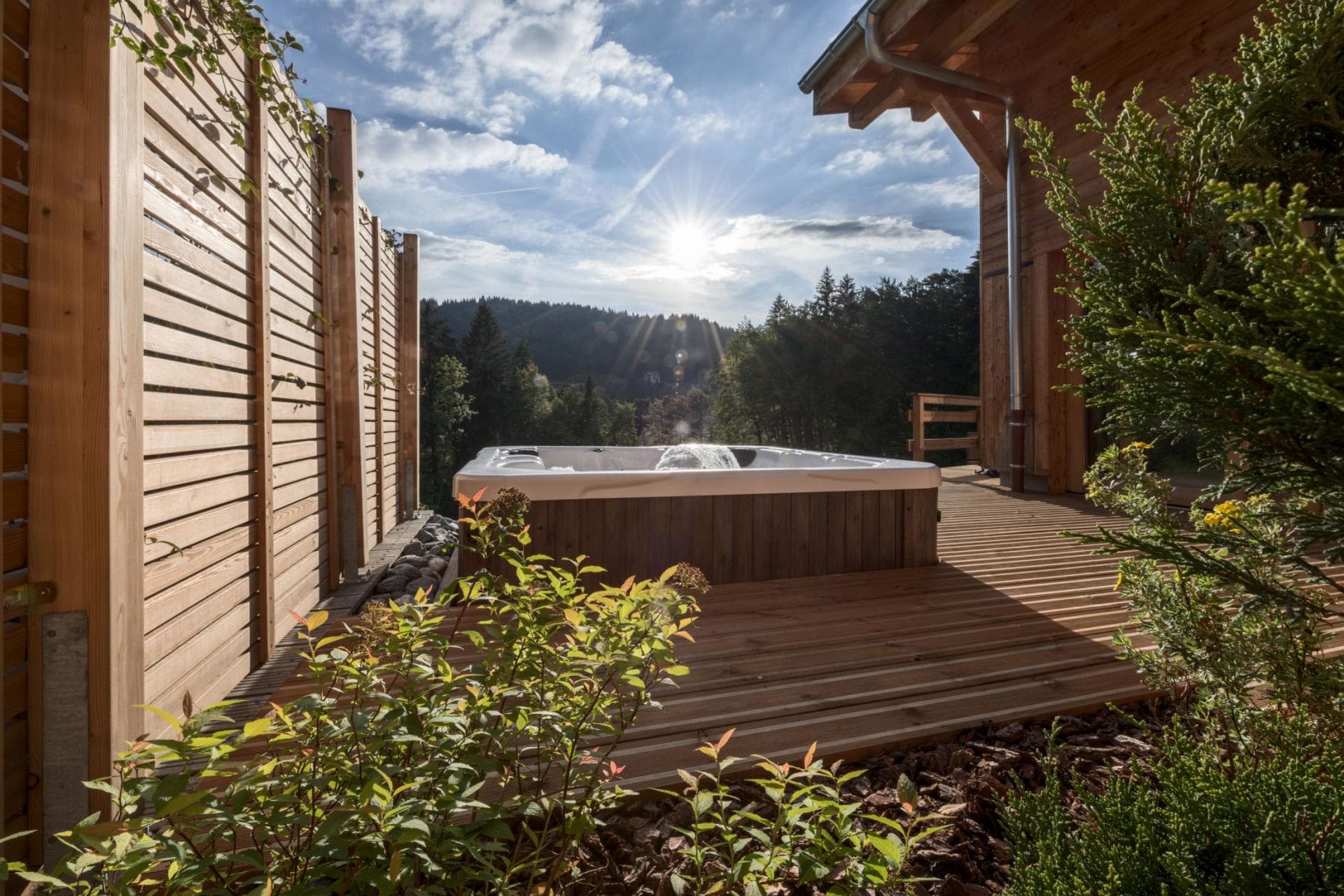 Outdoor hot tub with wooden privacy screen; forest views