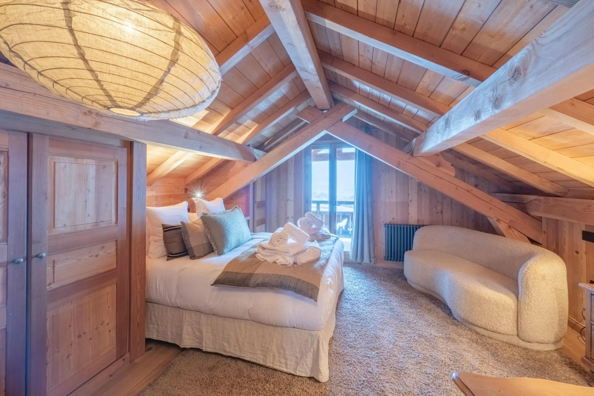 Bedroom beneath a vaulted timber ceiling with balcony access