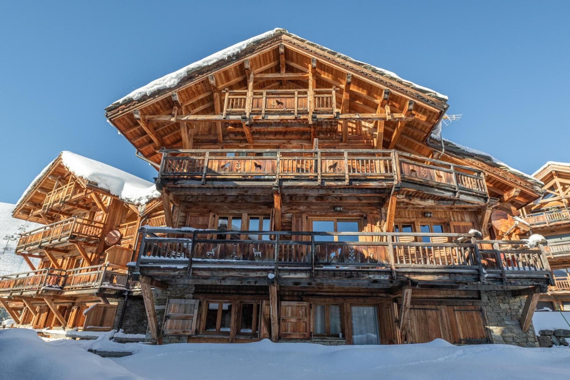 Multi-story timber chalet featuring balconies with decorative animal carvings